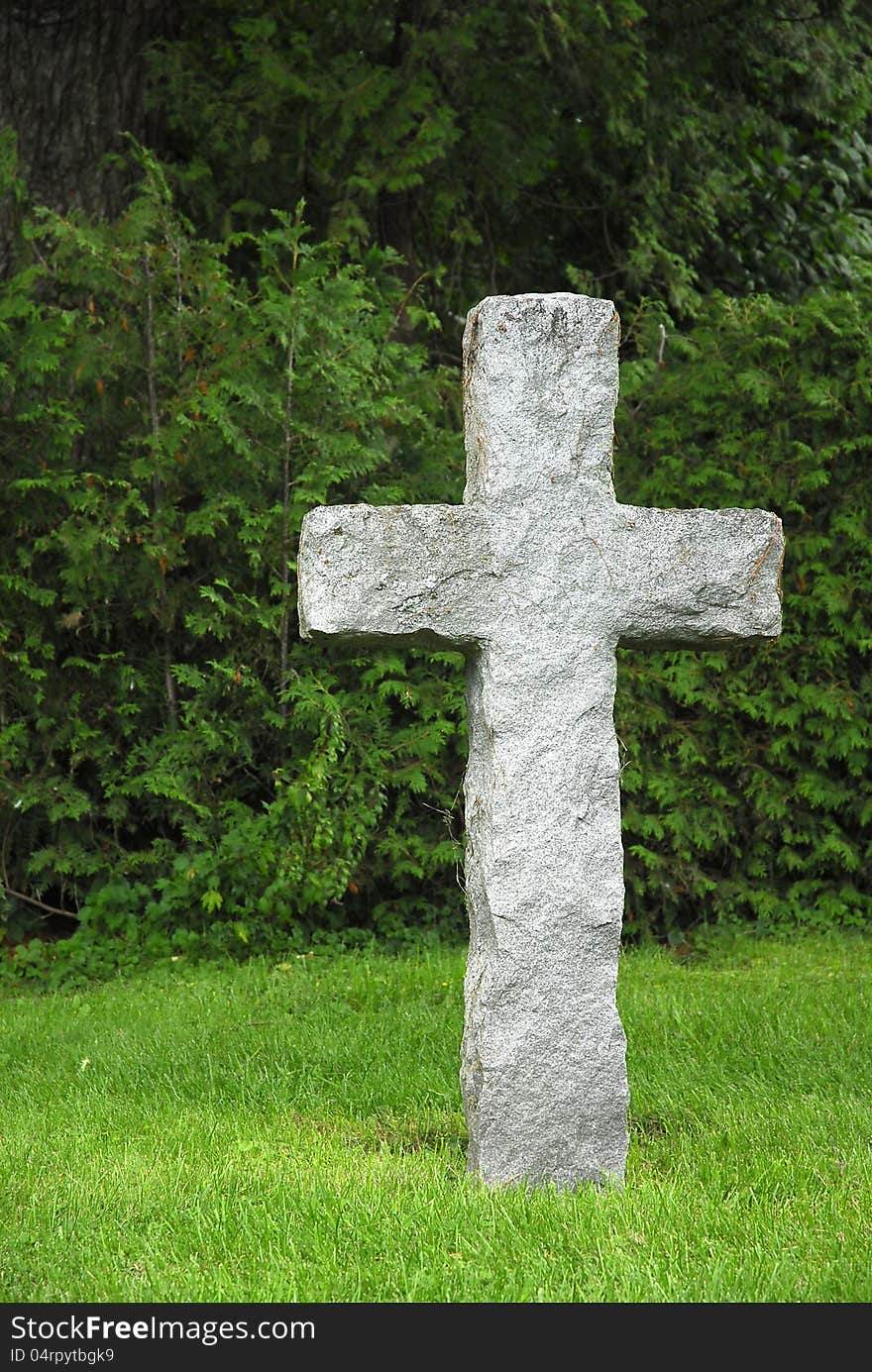 A stone cross stands against green foliage