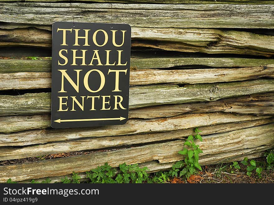 A sign on a wall of wooden poles restricts entry. A sign on a wall of wooden poles restricts entry