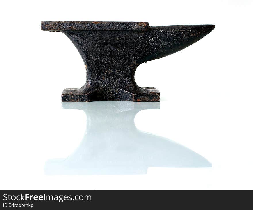 An old anvil on a glass plate with white background. An old anvil on a glass plate with white background