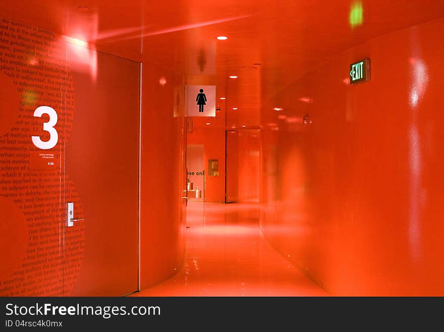 A totally red hallway with bathroom and exit sign