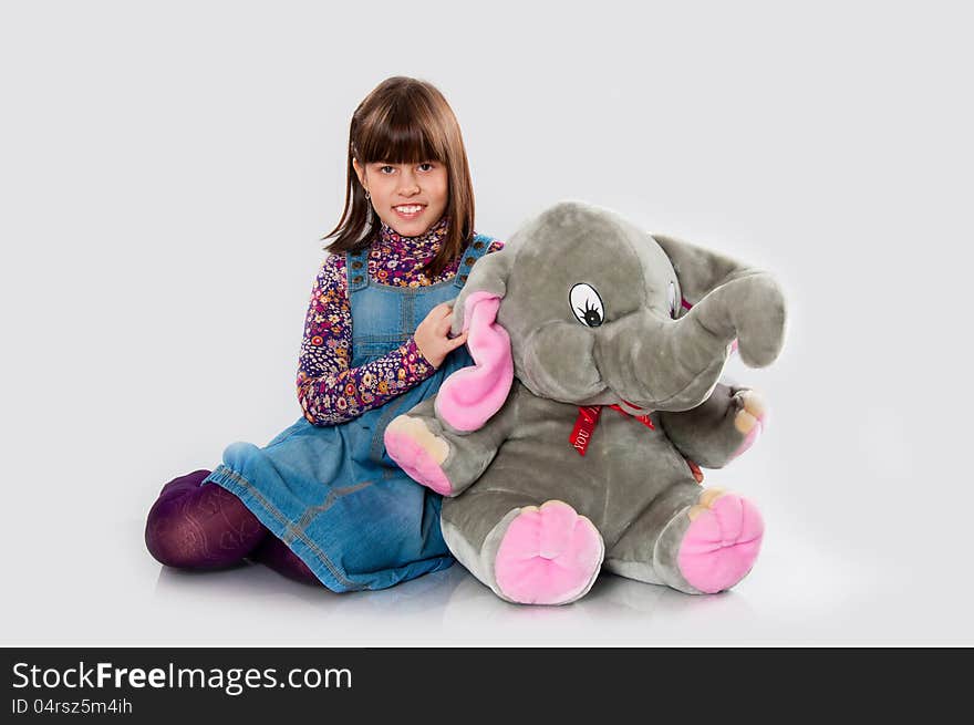 Cheerful girl playing with an elephant toy on white background