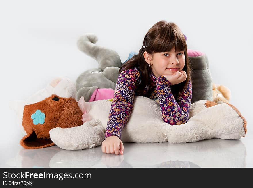 Cheerful girl playing with an elephant toy on white background