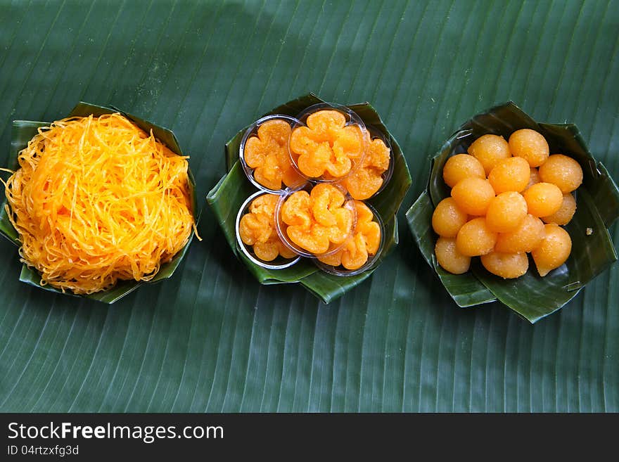 Thai assorted desserts which thier names are inspired by gold series. Foitong (Golden Hair), Tongyip (Tiny Gold Flower), Tongyod (Drops of Gold). Presented on green banana leaf cups.