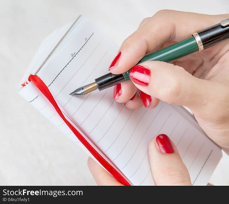 Close Up Of A Female Hand Holding A Pen About To Take Notes On A Blank Note Pad. Close Up Of A Female Hand Holding A Pen About To Take Notes On A Blank Note Pad