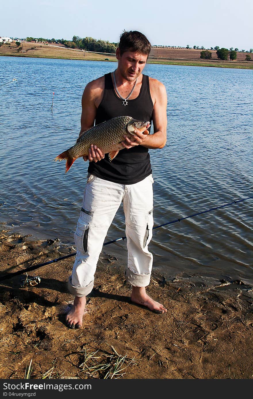 Fisherman with his big carp at a beautiful river.