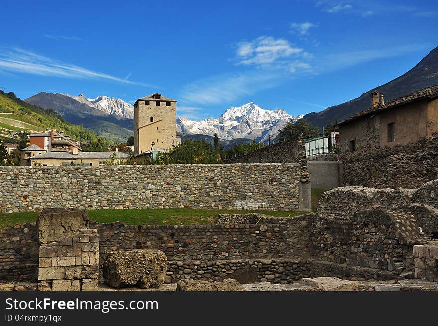 View of the Aosta city ancient Roman ruins and Alps peaks on the background. View of the Aosta city ancient Roman ruins and Alps peaks on the background.