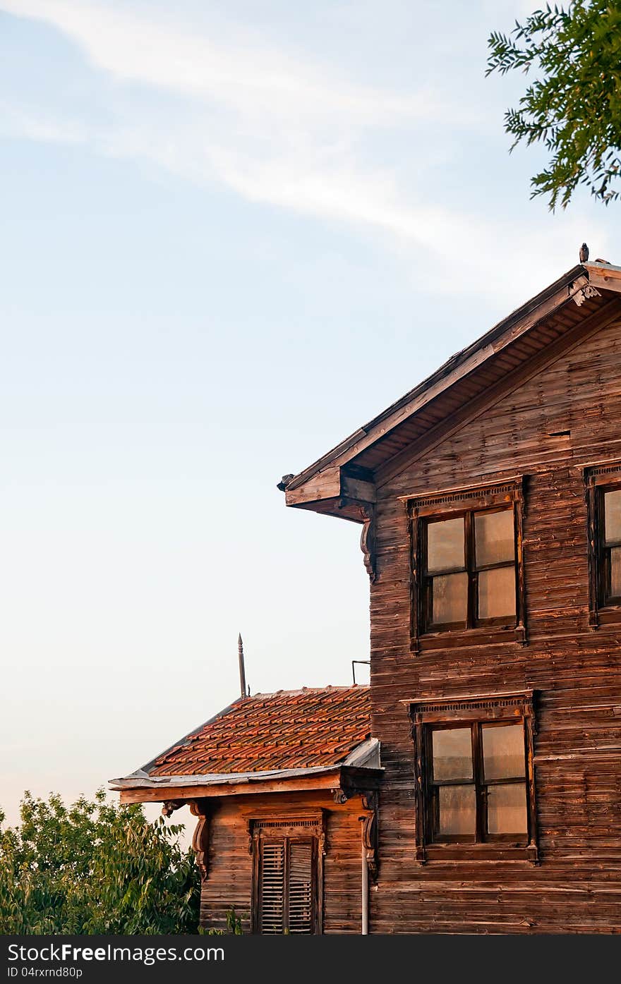 Vertical photo of a wooden house against blue sky.