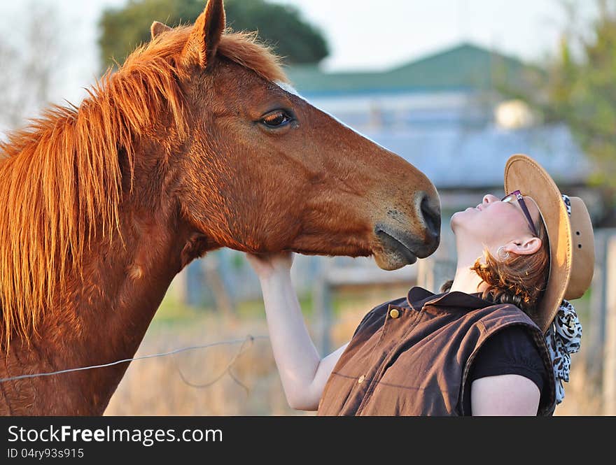 A horse leans in to give pretty young lady a kiss