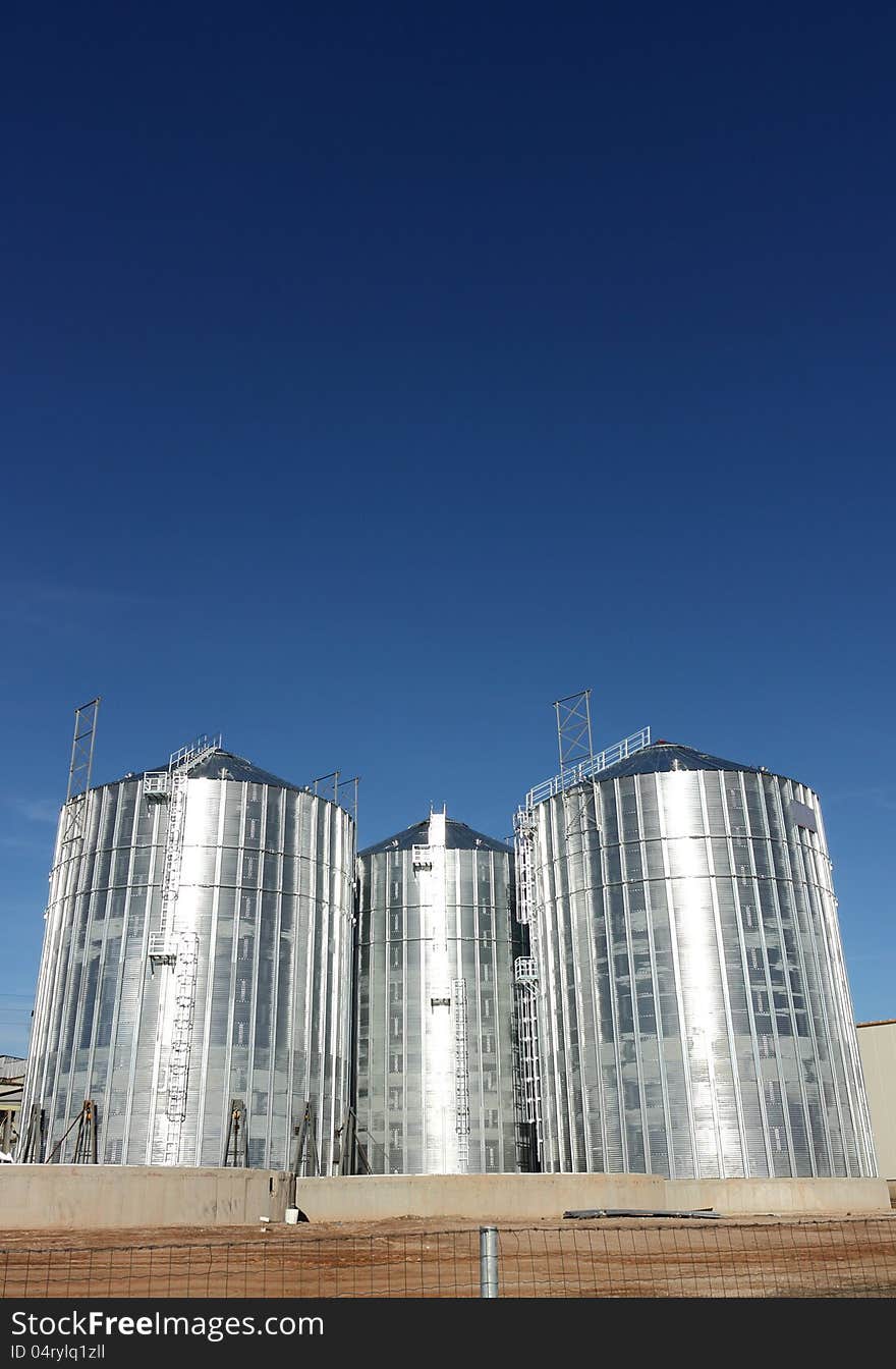 Metal silos on a clear blue sky background. Metal silos on a clear blue sky background