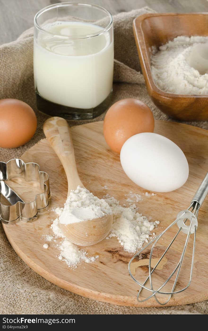 Ingredients for baking: flour, eggs, milk, cookie shape on a wooden board