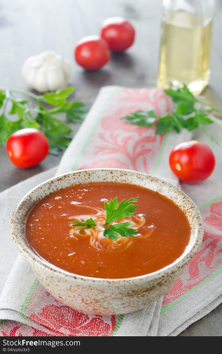 Hot tomato soup in ceramic bowl on the table, covered with a napkin