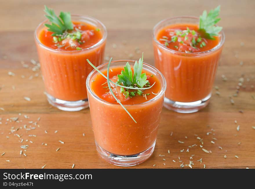 Cold tomato soup, portionwise, in glass jars decorated with greenery