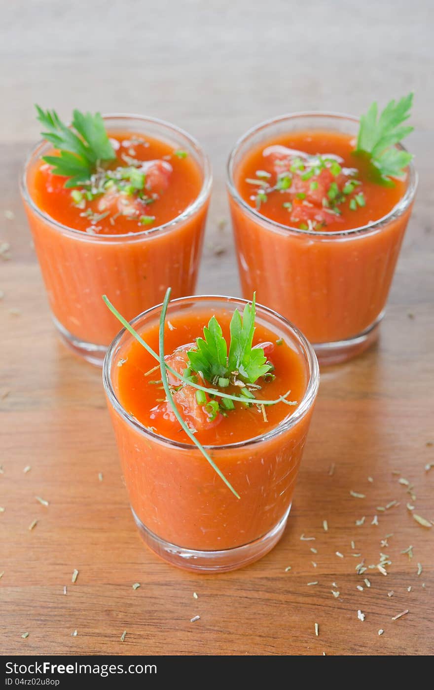 Cold tomato soup, portionwise, in glass jars decorated with greenery