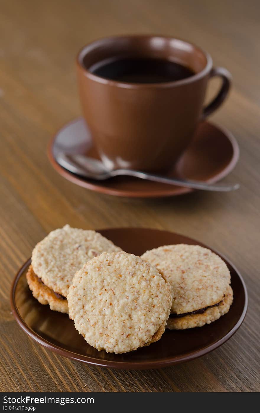 Walnut cookies on brown ceramic plate with a cup of coffee