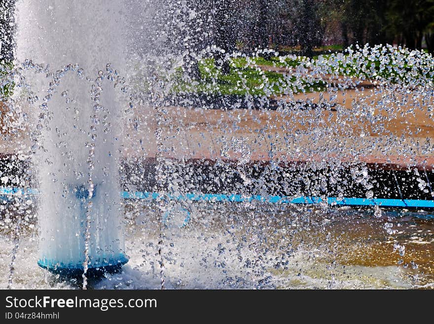 Sparkling splashes of a fountain in the bright sunny summer day. Sparkling splashes of a fountain in the bright sunny summer day