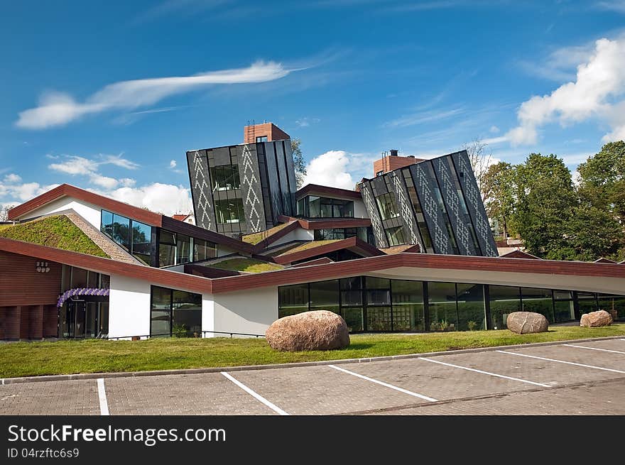 The inclined building of an original form against the cloudy sky