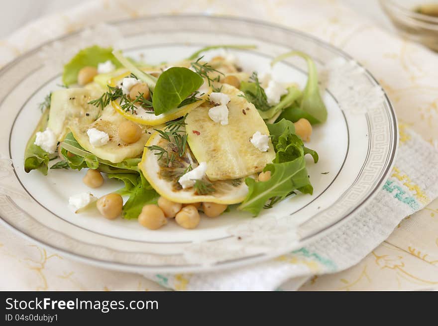 Chickpea salad with grilled zucchini and arugula on a white plate on a napkin. Chickpea salad with grilled zucchini and arugula on a white plate on a napkin