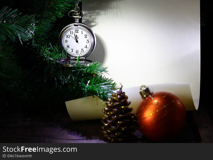 New Year decoration. Vintage pocket watch hanging near firtree against blank scroll. New Year decoration. Vintage pocket watch hanging near firtree against blank scroll