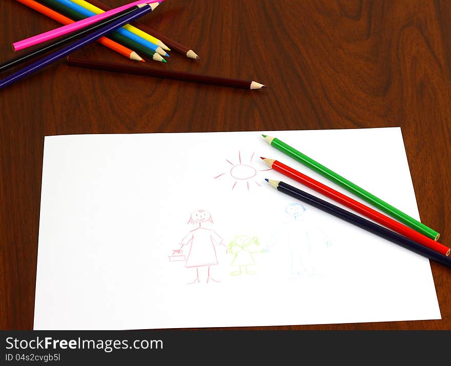 Three color pencils lie on table over the drawing. Bunch of other pencils lies behind