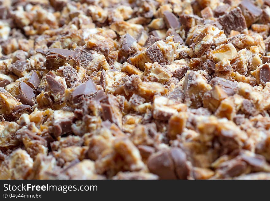 Closeup image of chopped bars of chocolate, caramel and biscuit