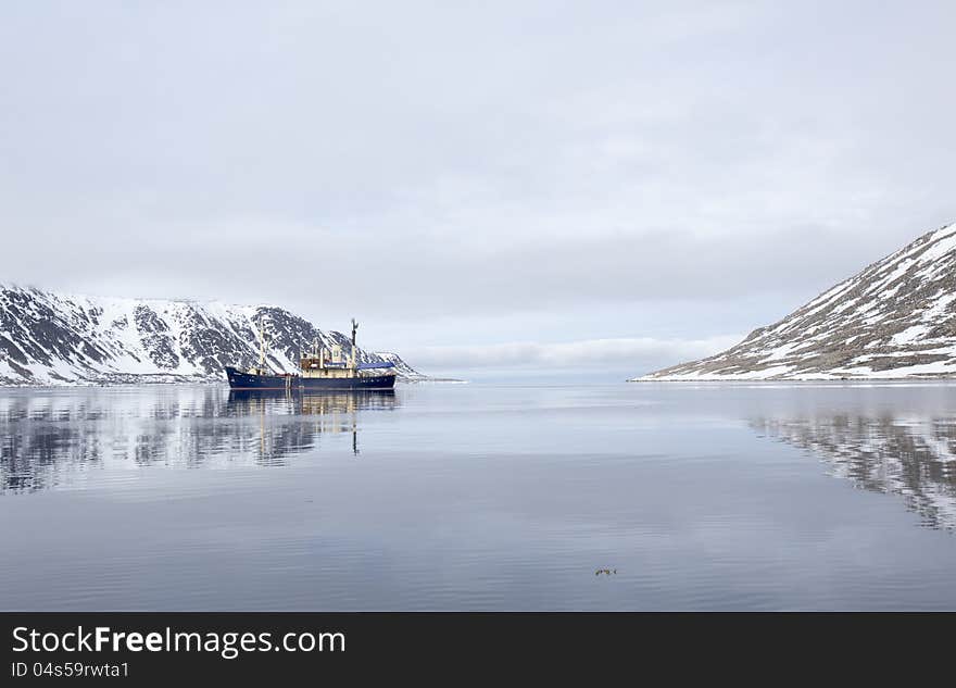 A tourist boat anchored in a beautiful bay, surrounded by Spitsbergen, Svalbard. A tourist boat anchored in a beautiful bay, surrounded by Spitsbergen, Svalbard.