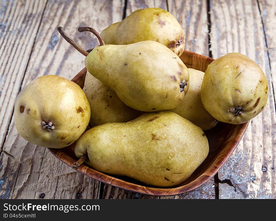 Fresh pears in a wooden bowl on table