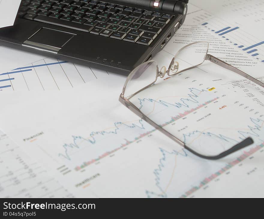 Laptop and glasses on business papers