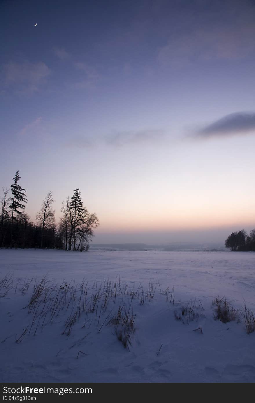 Snowy landscape after sunset with the moon in the sky. Snowy landscape after sunset with the moon in the sky