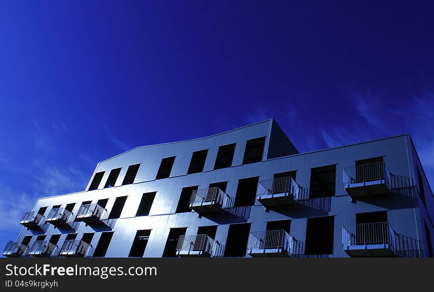 Building with balconies on a blue background in the midday sun. Building with balconies on a blue background in the midday sun