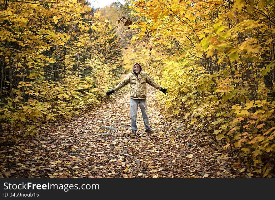 A man throwing leaves in the air on a walk through the woods in Autumn. A man throwing leaves in the air on a walk through the woods in Autumn.