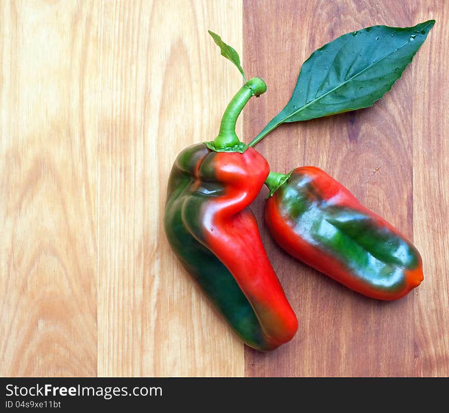 Two variegated peppers on wooden cutting board. Two variegated peppers on wooden cutting board.