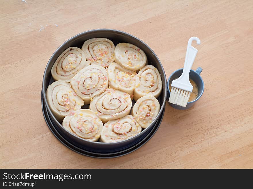 A decorated sweet cinnamon roll cake in a baking form rising and waiting for the baking. A decorated sweet cinnamon roll cake in a baking form rising and waiting for the baking.