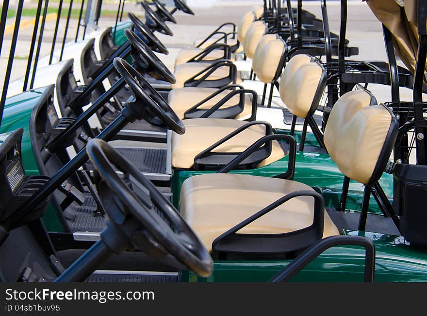 Row of golf carts closeup showing row of steering wheels and seats