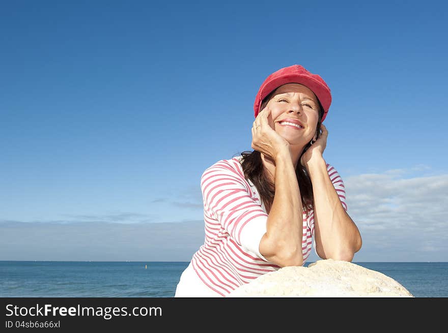 Portrait of relaxed and attractive looking senior woman enjoying active retirement and leisure time at sea, with ocean and blue sky as background and copy space. Portrait of relaxed and attractive looking senior woman enjoying active retirement and leisure time at sea, with ocean and blue sky as background and copy space.