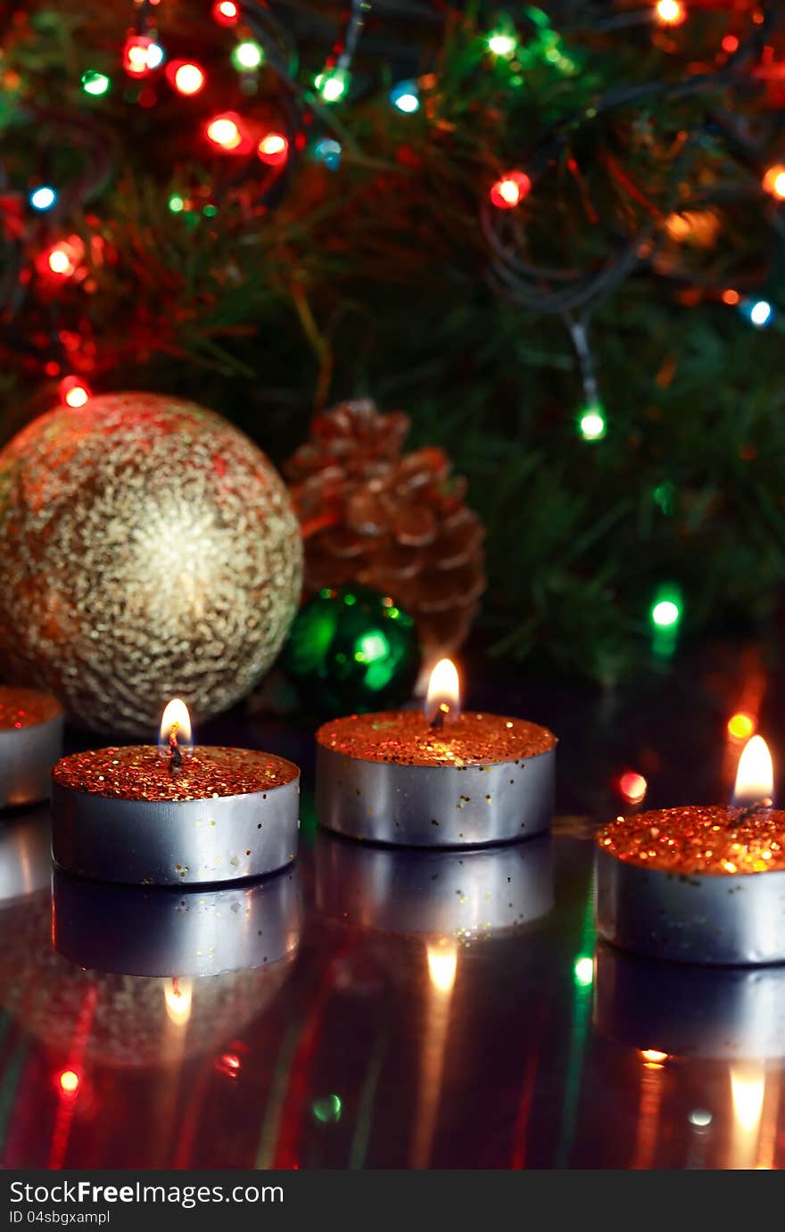 Few lighting candles on glass surfase with reflection on background with Christmas decorations. Few lighting candles on glass surfase with reflection on background with Christmas decorations