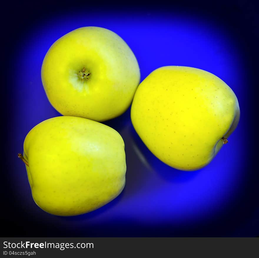 Three yellow apples on blue background. Three yellow apples on blue background.