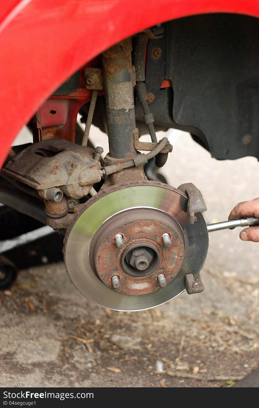 Mechanic removing brake pads from old disc brake.