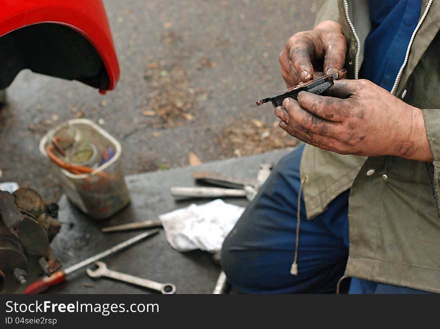 Mechanic holding new brake pad and lubricating it with copper oil. Mechanic holding new brake pad and lubricating it with copper oil.