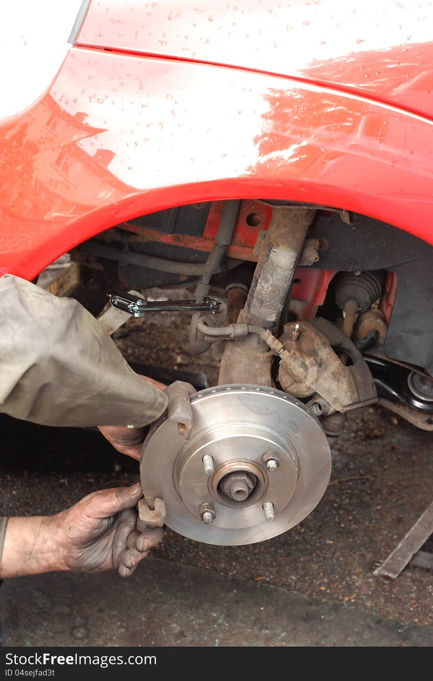 Mechanic tests out old caliper on new ventilated disc for proper movement. Mechanic tests out old caliper on new ventilated disc for proper movement.