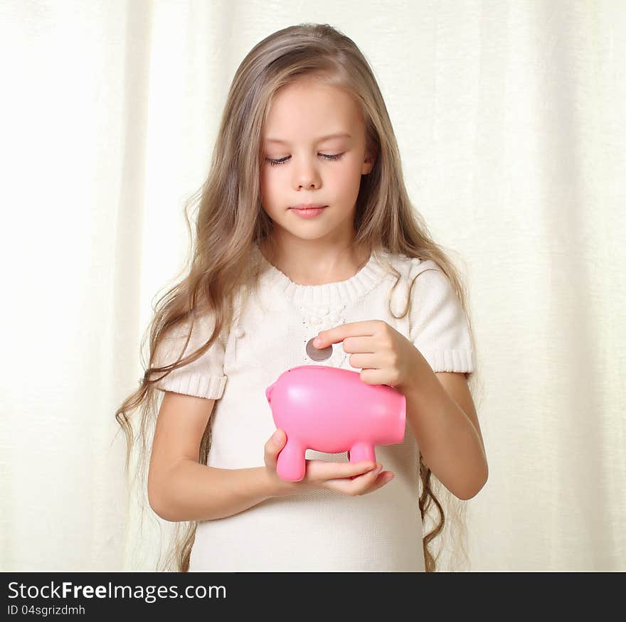 Little Blond Girl Puts Coin Into Piggy Moneybox