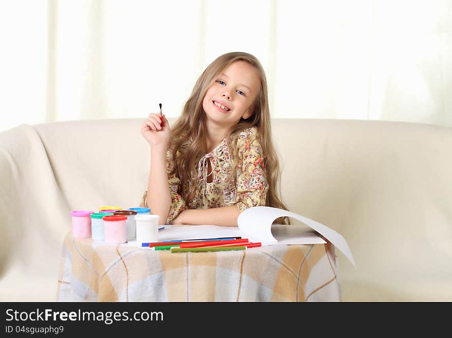 Little blond girl drawing at home on sofa