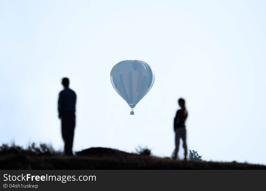 People are looking at a balloon flying away in the distance