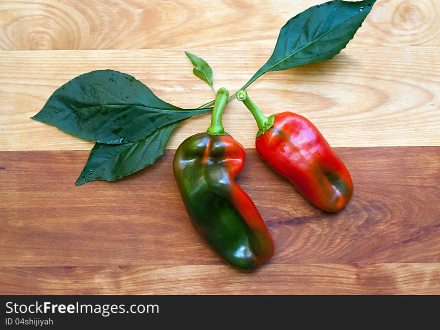 Two variegated sweet peppers (Red Roaster Hybrid) on wooden cutting board. Two variegated sweet peppers (Red Roaster Hybrid) on wooden cutting board.