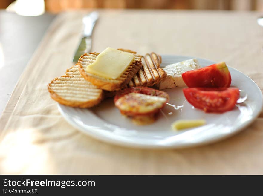 On a white plate crisp bread with cheese and tomatoes. On a white plate crisp bread with cheese and tomatoes