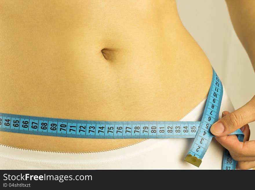 Young woman measures waist volume on a white background. Young woman measures waist volume on a white background