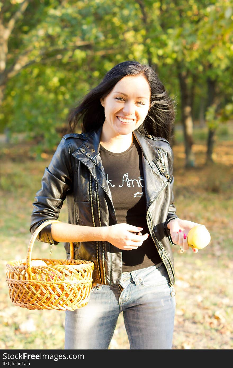 Happy woman carrying a basket and apple walking in a park. Happy woman carrying a basket and apple walking in a park.