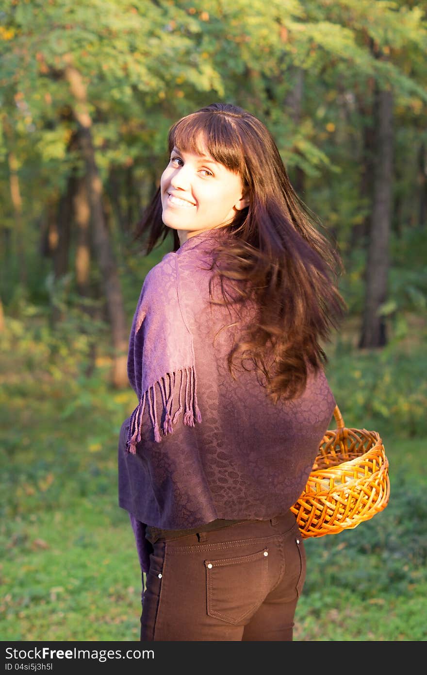 Beautiful woman walking in woodland looking back over her shoulder with her face caught in a beam of sunlight. Beautiful woman walking in woodland looking back over her shoulder with her face caught in a beam of sunlight