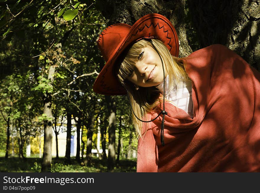 A beautiful girl in a red hat leaned against to the thick barrel of tree. A beautiful girl in a red hat leaned against to the thick barrel of tree.