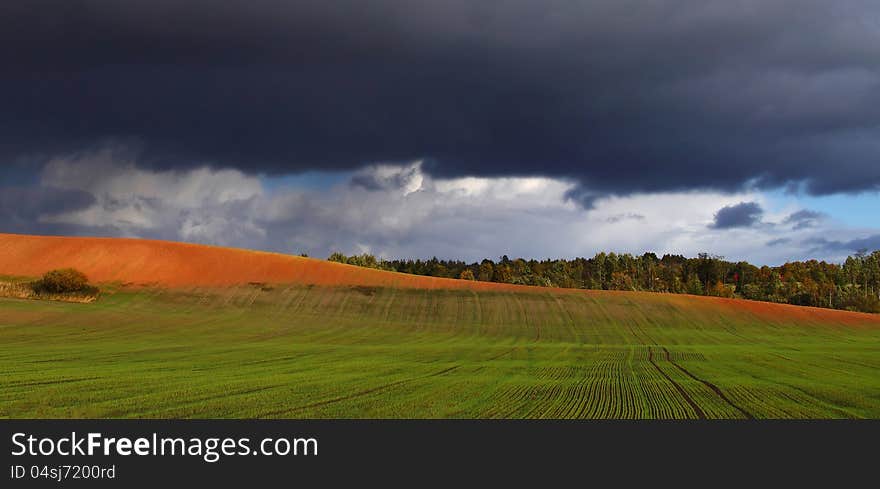 Green meadow and bright hill under dark cloudy sky. Green meadow and bright hill under dark cloudy sky