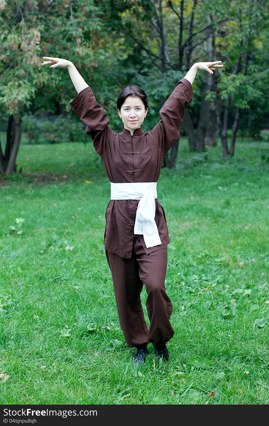 Zen pretty woman practicing exercise chi kung, tai chi, kung fu or yoga in natural park